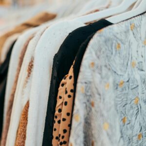 A close-up view of fashionable clothes hanging on racks in a boutique setting, showcasing various patterns and textures.
